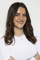 Eine junge Frau mit langen braunen Haaren lächelt freundlich in weißem Oberteil